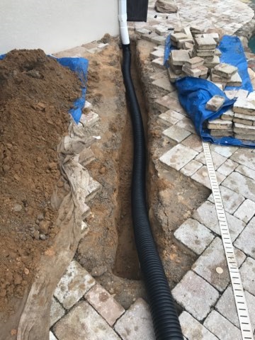 Orlando Florida residential landscape drain pipe being installed beneath pavers.